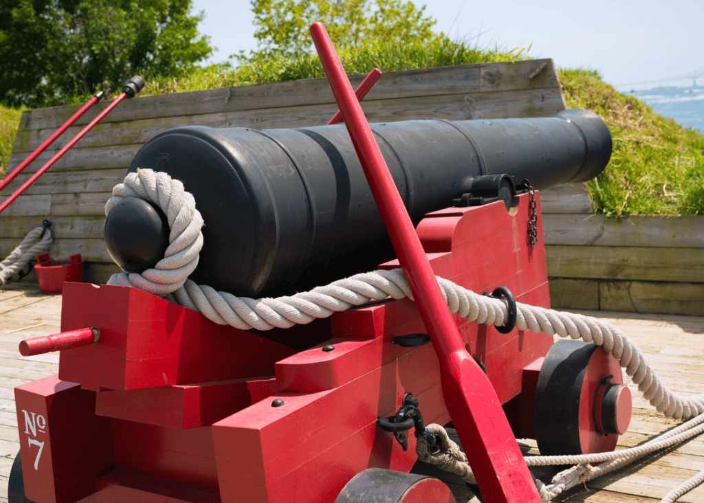 A historic black cannon mounted on a red wooden carriage overlooks the harbor at Fort McHenry in Baltimore, Maryland, the site that inspired Francis Scott Key to write the Star Spangled Banner.
