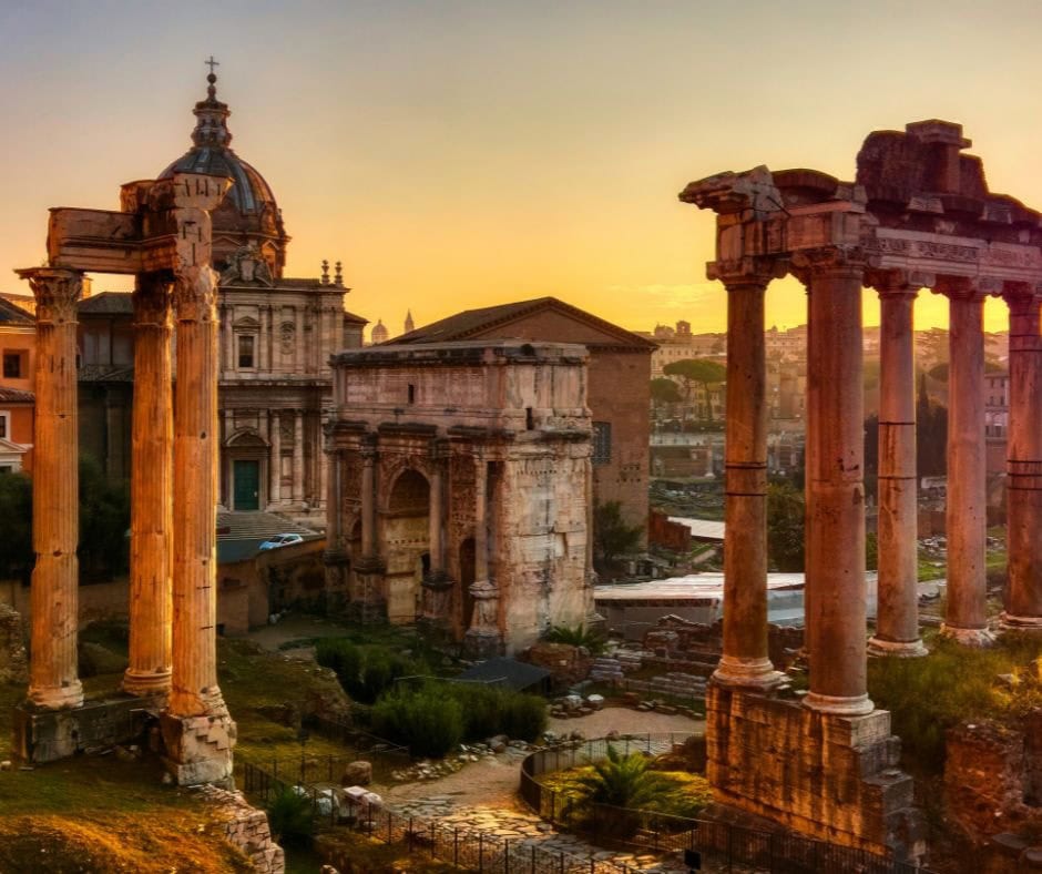 Ancient columns and ruins of the Roman Forum in Rome illuminated by warm evening light.