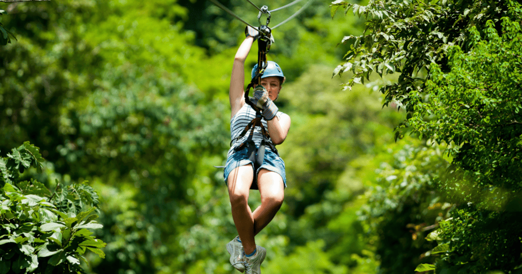 Woman zip lining through the lush green rainforest canopy in Costa Rica.