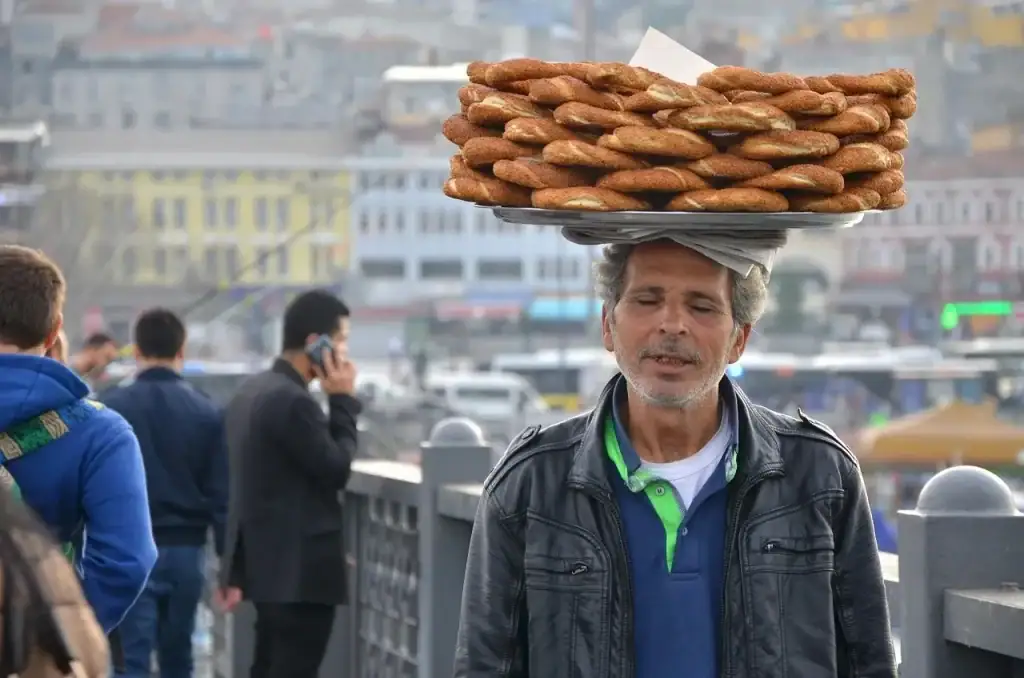 Street vendor in Istanbul, Turkey, carrying a tray stacked with traditional sesame covered simit bread.