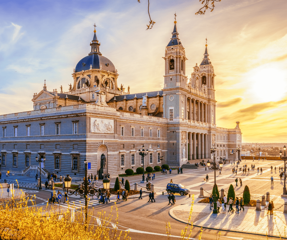 Almudena Cathedral in Madrid, Spain at sunset with visitors walking along the plaza