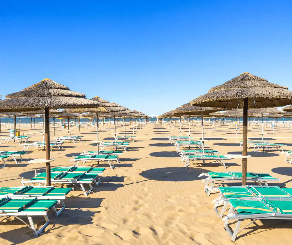 Wide sandy Adriatic beach in Rimini with rows of colorful umbrellas and shallow turquoise water stretching to the horizon