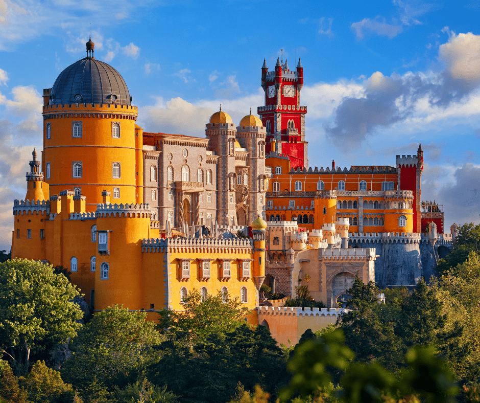 Colorful and ornate Pena Palace rising above the treetops in Sintra Portugal with its distinctive yellow and red towers against a dramatic cloudy sky.