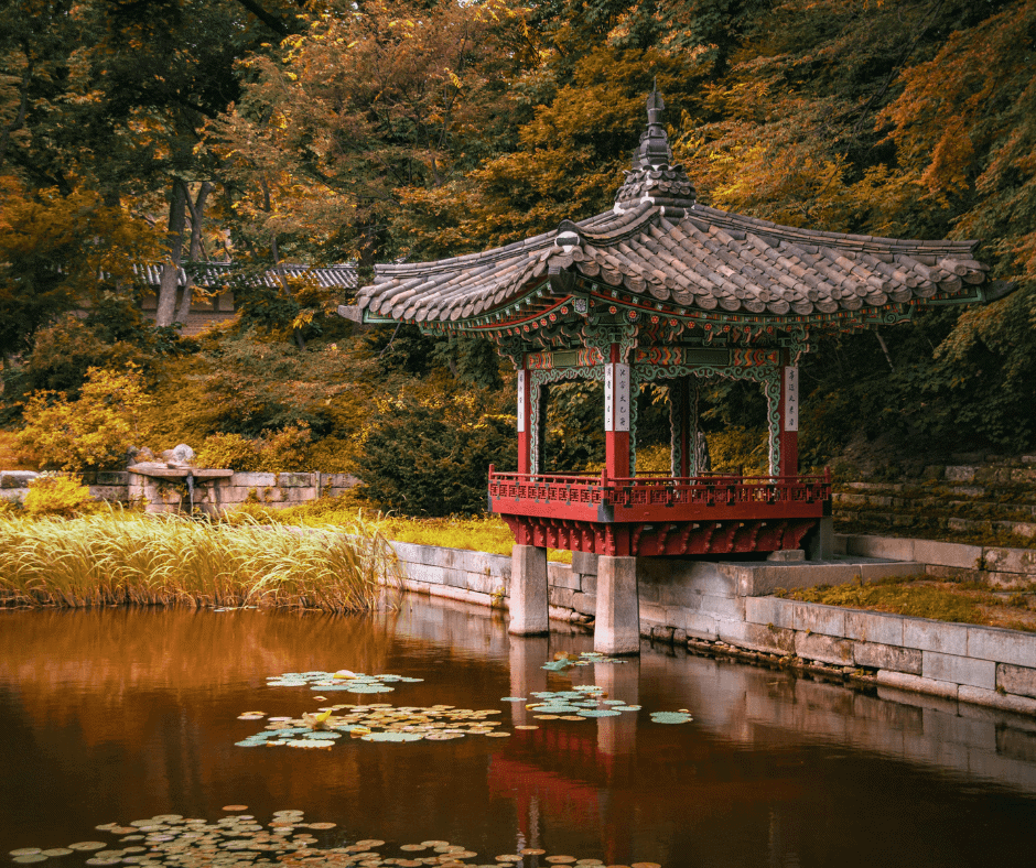 Traditional Korean pavilion overlooking a peaceful pond surrounded by colorful autumn foliage in South Korea.