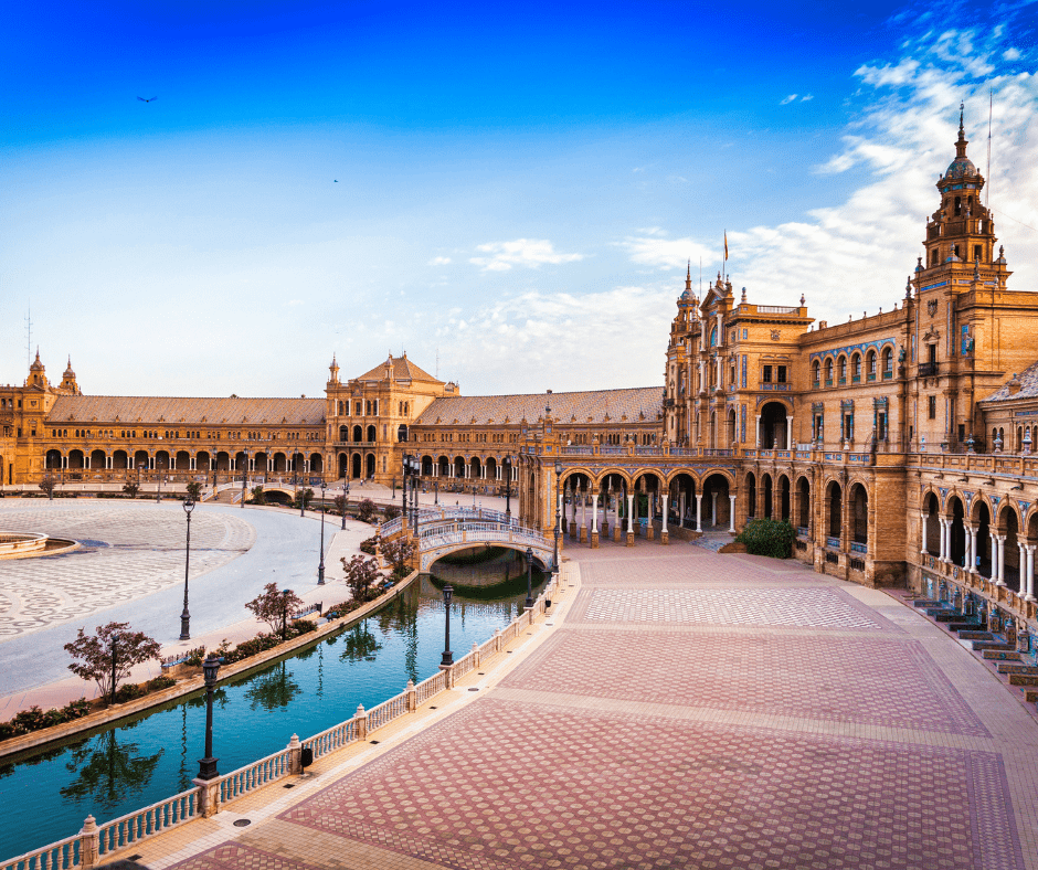 Plaza de España in Seville, Spain with ornate architecture, a canal, and a bridge on a clear sunny day