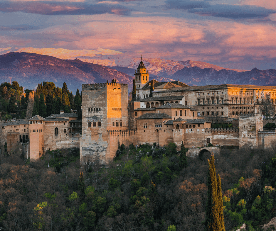 Alhambra palace and fortress in Granada, Spain at sunset with the Sierra Nevada mountains in the background