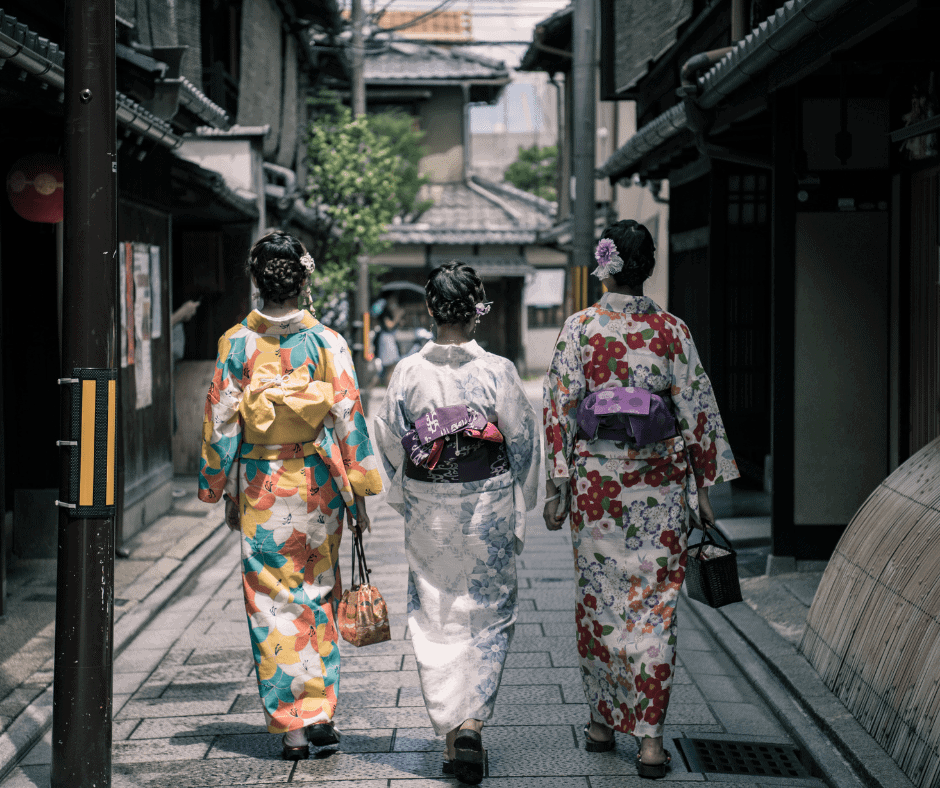 Three women wearing colorful traditional kimonos walking through a historic street in Kyoto, Japan, showcasing the city's timeless culture and heritage.