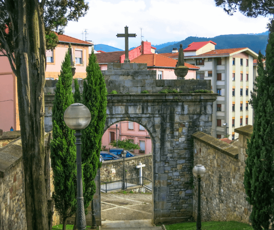 Stone archway with a cross and cypress trees in a small town in northern Spain