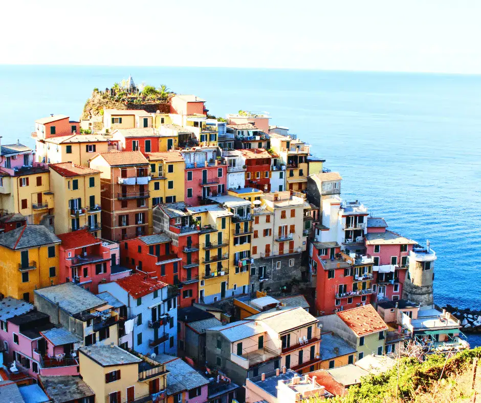 Five colorful hillside villages of Cinque Terre clinging to sea cliffs in Liguria, Italy, with terracotta rooftops and a calm harbor below