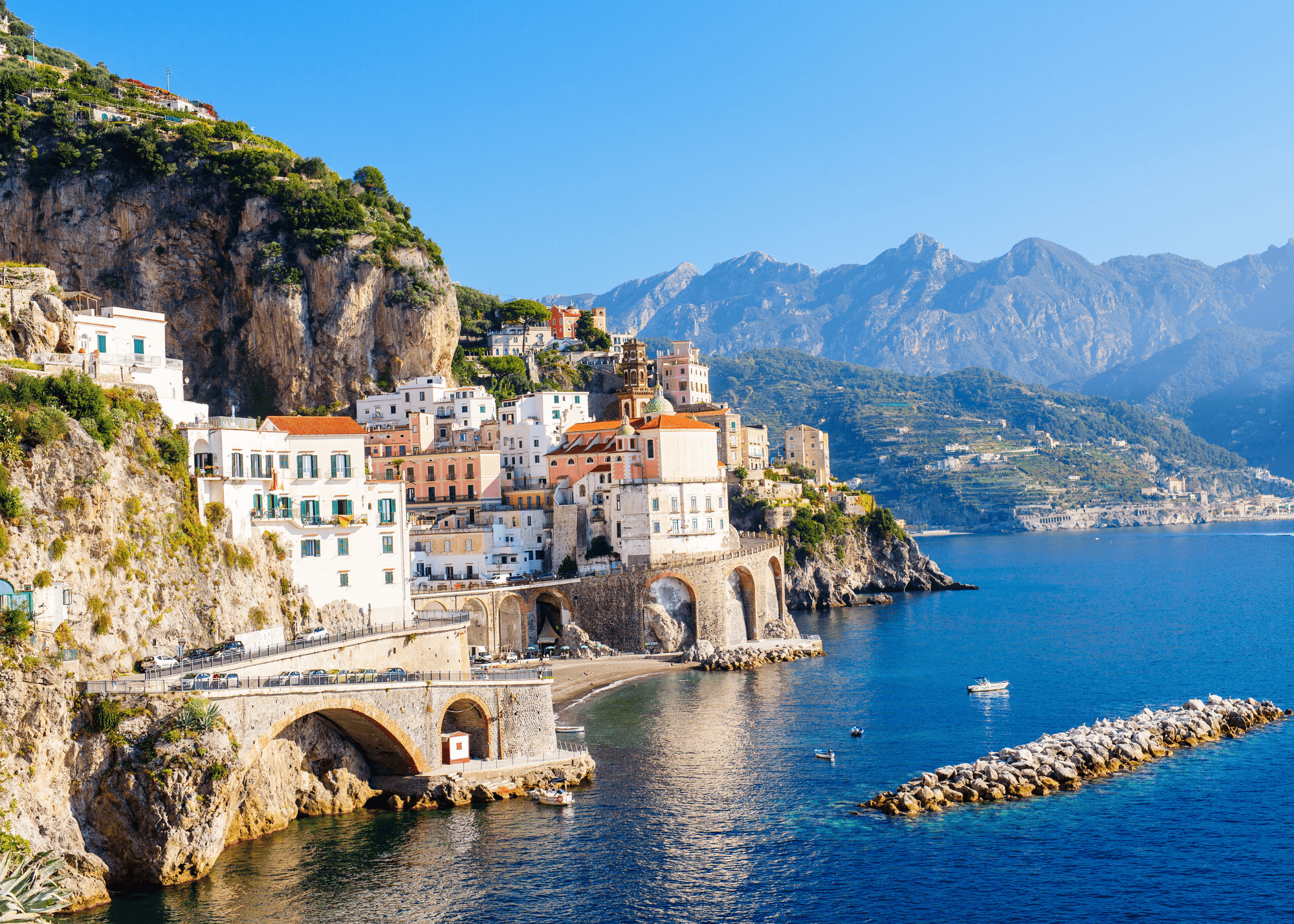Atrani village on the Amalfi Coast Italy with colorful buildings cascading down the cliffs to the sea with mountains in the background