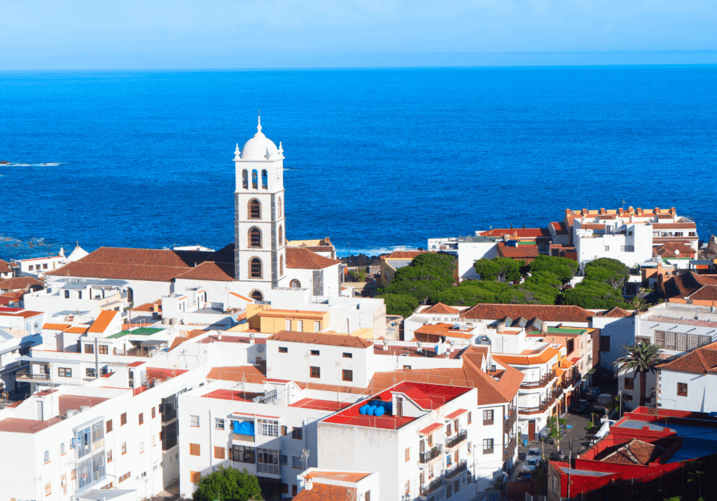Whitewashed town with a church tower and red rooftops overlooking the Atlantic Ocean in Tenerife, Canary Islands