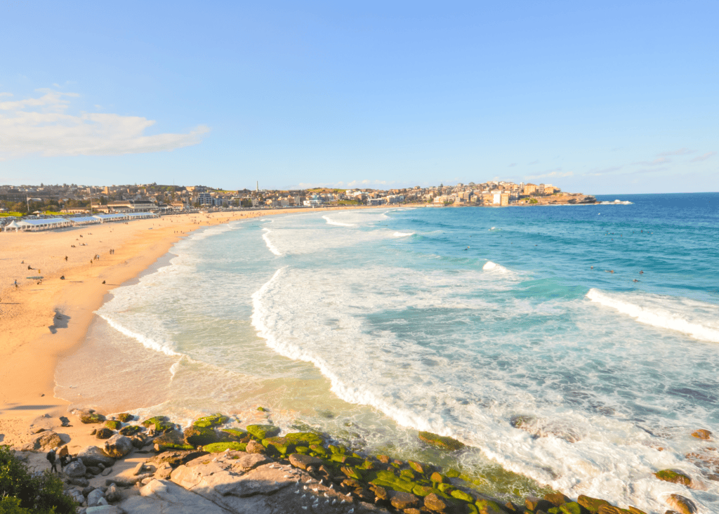 Aerial view of iconic Bondi Beach crescent with golden sand, turquoise waves and surfers in Sydney Australia