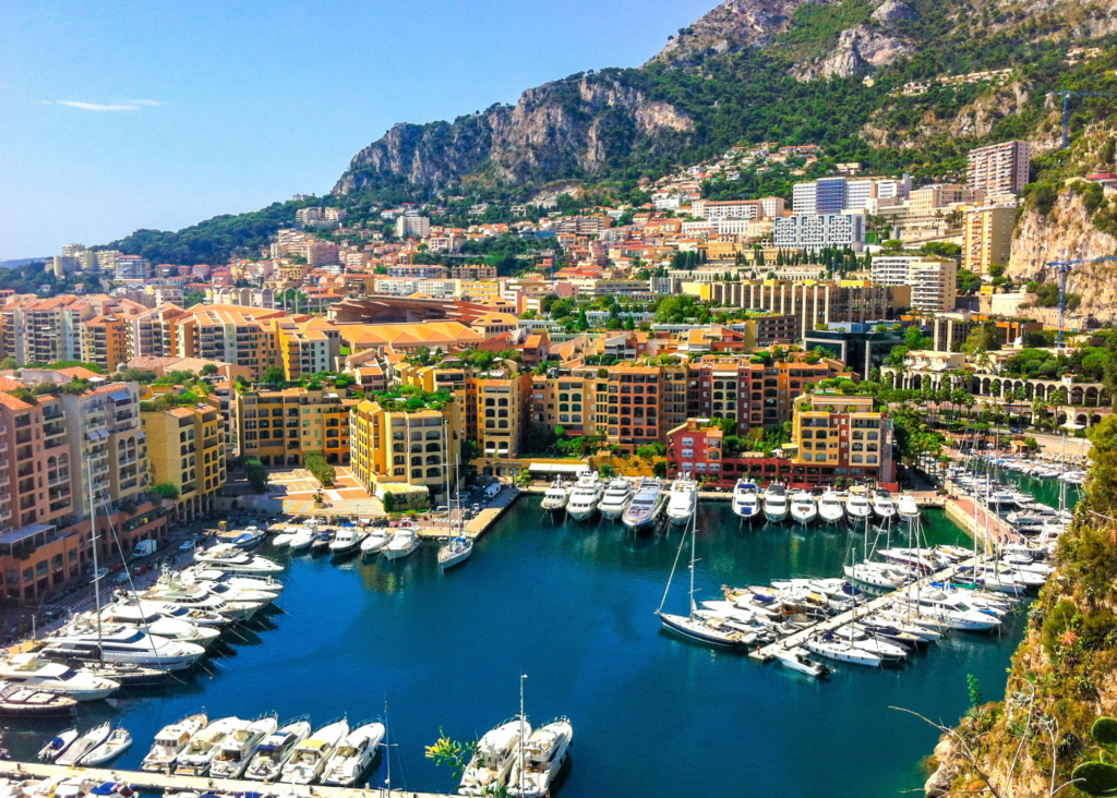 Monaco harbor with luxury yachts, colorful buildings and mountain backdrop on the French Riviera