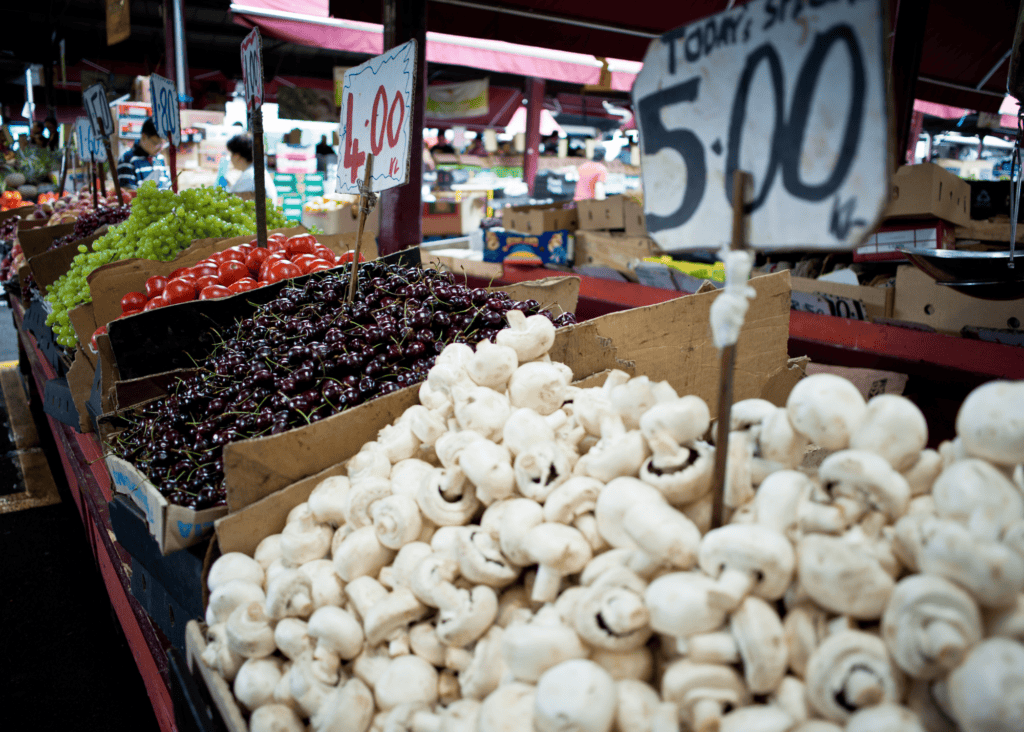 Fresh produce stalls with mushrooms, cherries and grapes at Queen Victoria Market in Melbourne Australia