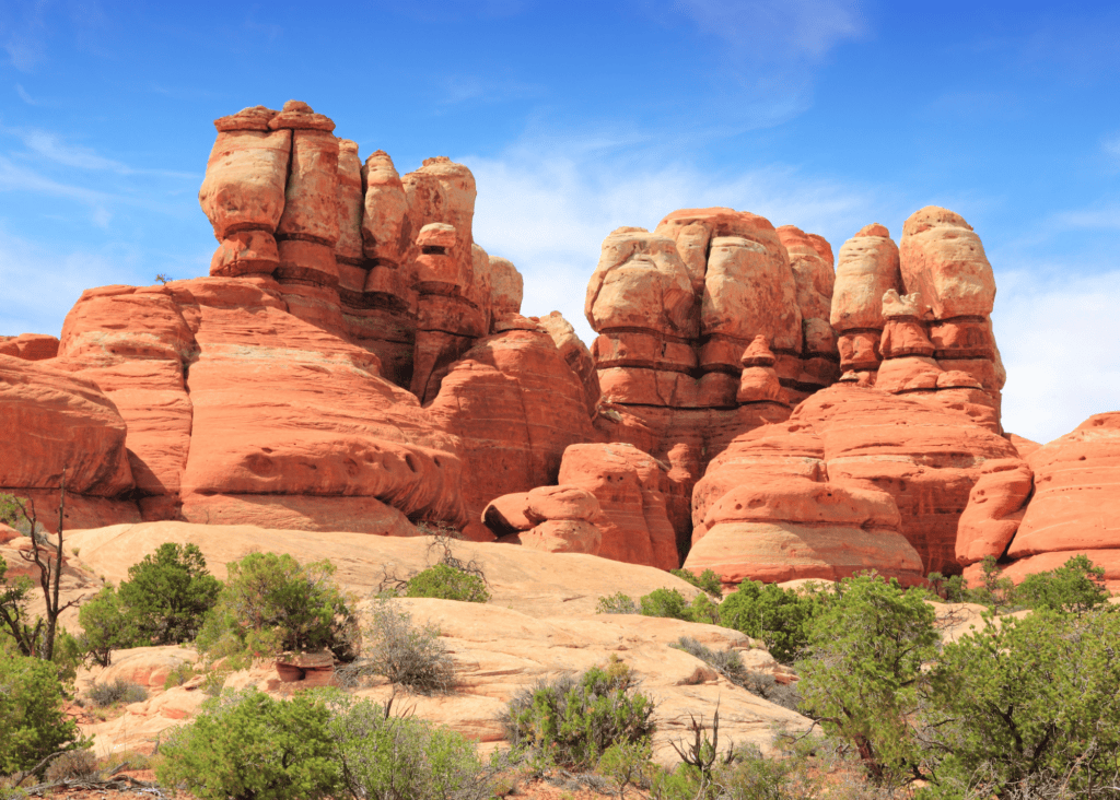 Towering red and cream sandstone rock formations rising above desert scrub in Canyonlands National Park Utah.