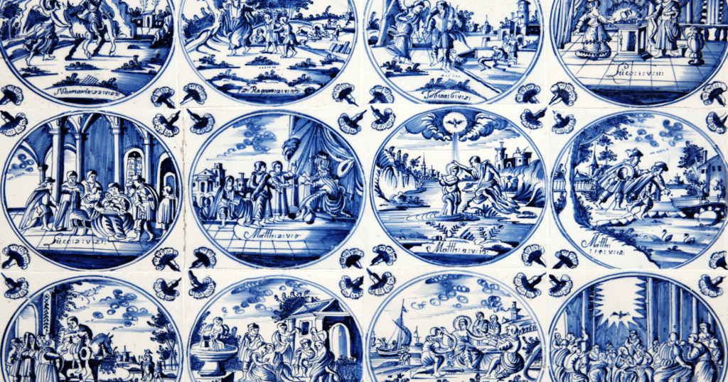 A grid of antique Delft blue and white ceramic tiles hand painted with detailed biblical and pastoral scenes in the traditional Dutch pottery style dating to the 17th century.