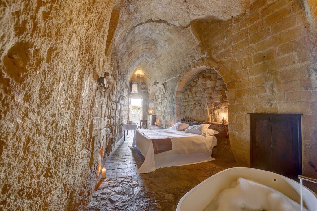 Bedroom and bathtub inside a cave suite at Sextantio Le Grotte della Civita in Matera, Italy