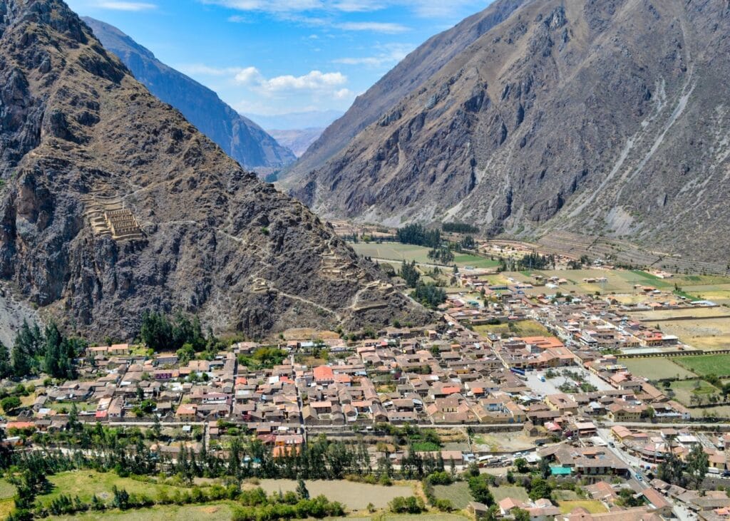 Aerial view of the town of Ollantaytambo in the Sacred Valley of Peru with ancient Inca terraces carved into the steep mountainside above and the valley stretching into the distance