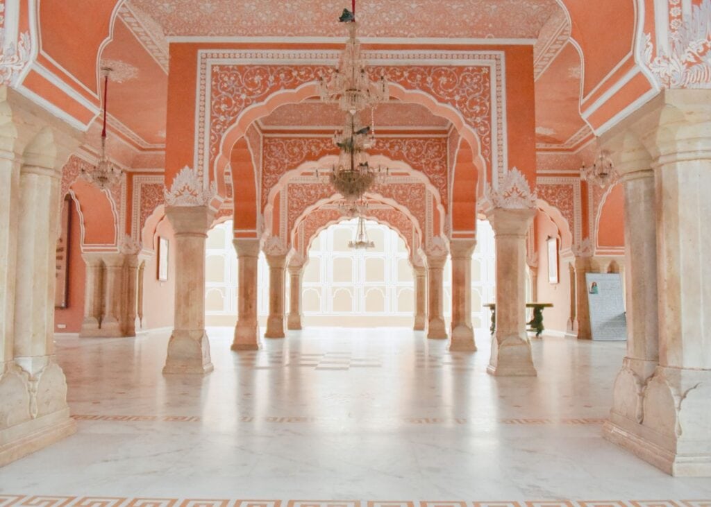 Pink and white scalloped archways with chandeliers inside City Palace in Jaipur,