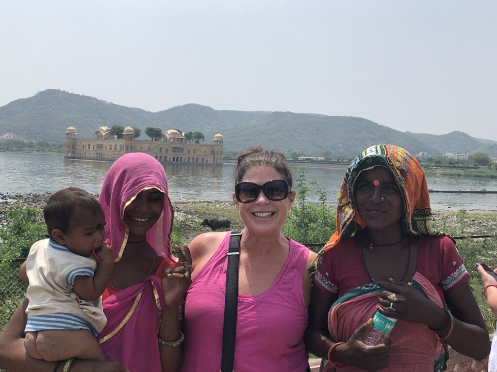 Traveler posing with local women and a child near Jal Mahal, the Water Palace, on Man Sagar Lake in Jaipur, India.