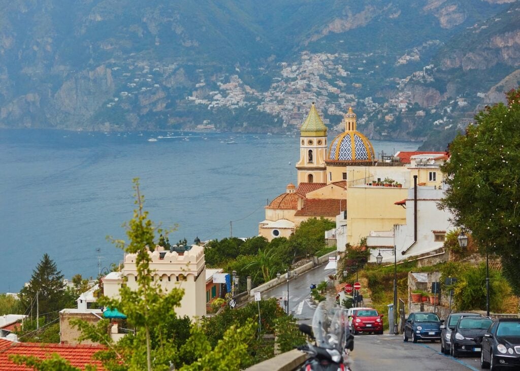 View of Praiano overlooking the colorful church dome and the Mediterranean Sea on the Amalfi Coast.