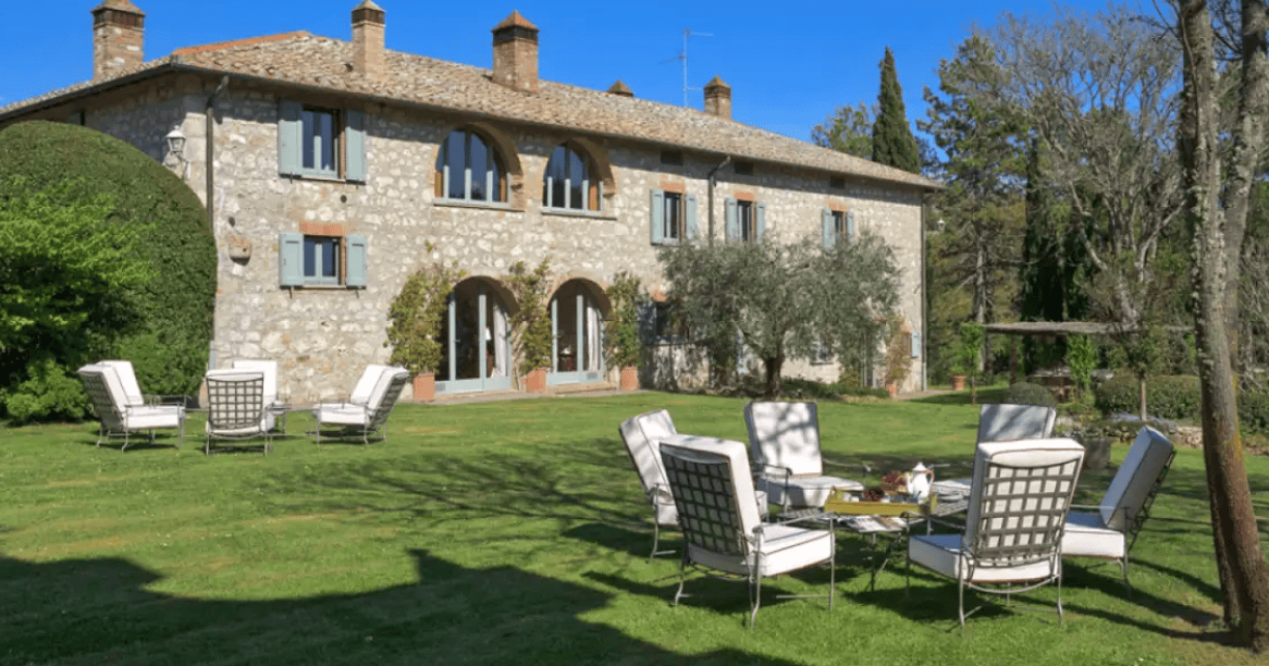 Traditional stone villa in Tuscany with a landscaped garden and outdoor seating area.