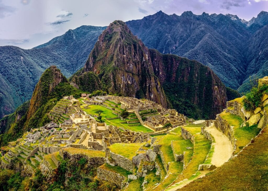 The stone terraces and ruins of Machu Picchu set against the green Andes mountains in Peru.