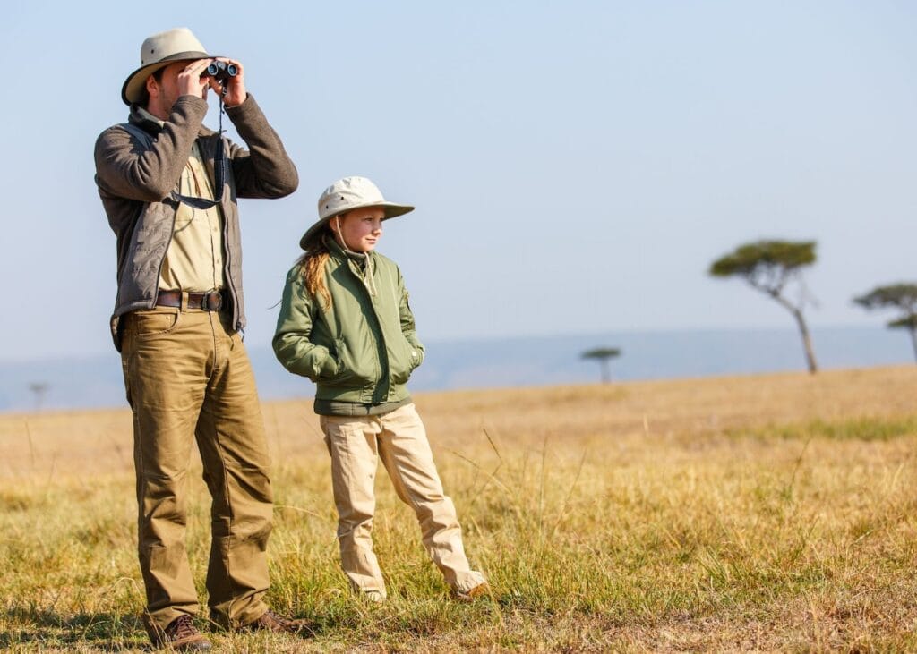 Father and daughter dressed in neutral safari layers and hats, an example of practical safari packing