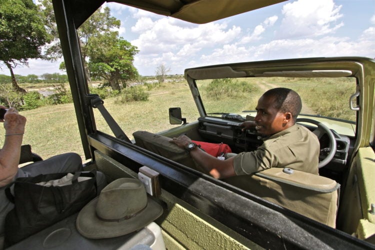 Safari guide talking with guests from the driver's seat of an open safari vehicle