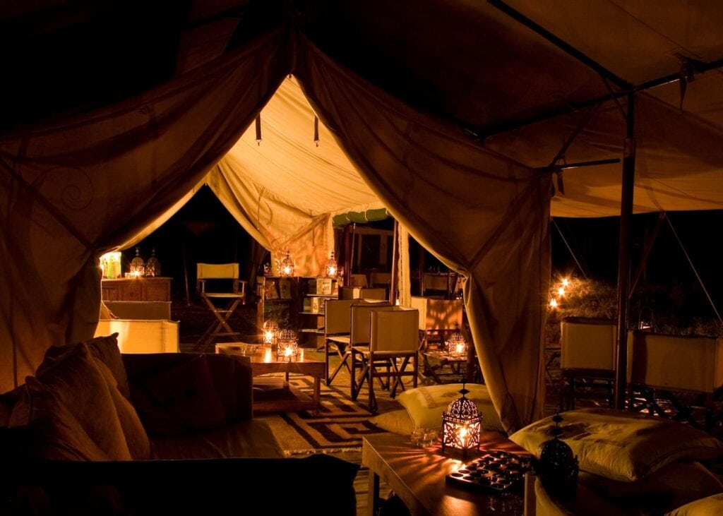 Candlelit safari tent lounge area with lanterns and seating at night