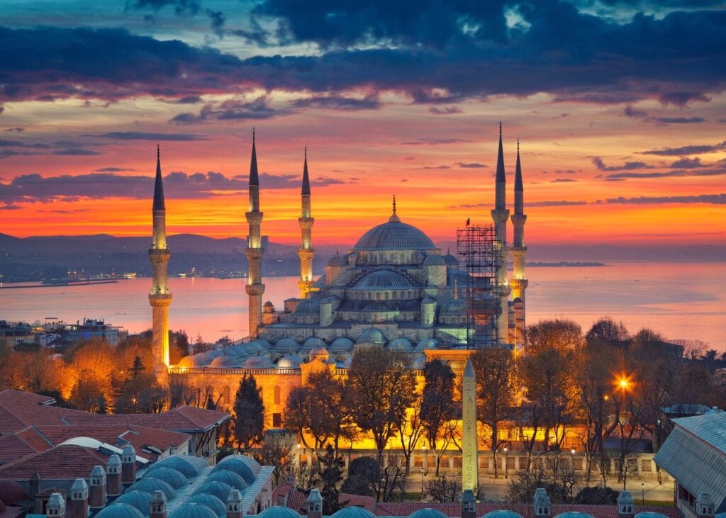Blue Mosque illuminated at sunset with colorful sky over Istanbul, Turkey.